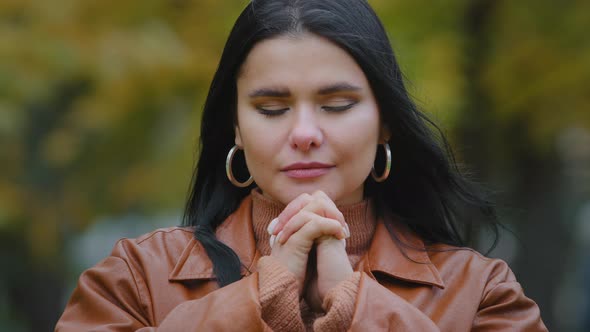Young Calm Hispanic Woman Standing Outdoors Meditating with Closed Eyes Holding Hands Clasped