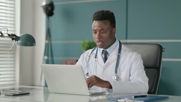 African Doctor Talking on Video Call on Laptop in Office