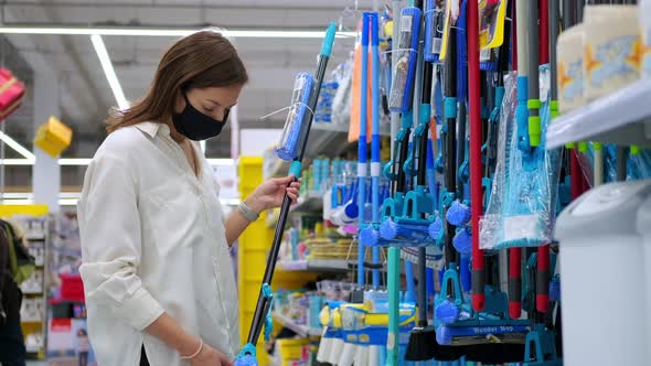 Young Woman with Face Mask is Shopping in Store with Home Goods Choosing Mop / Videohive