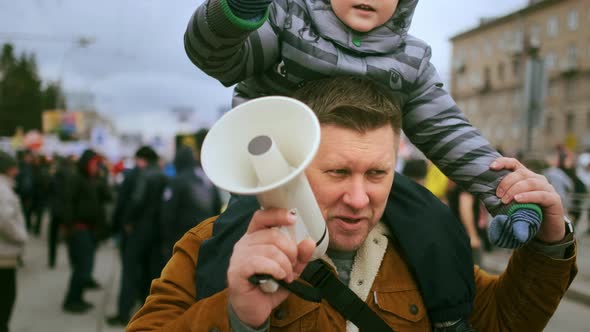 Father with Bullhorn Megaphone and Sitting Boy Kid on Political Demonstration