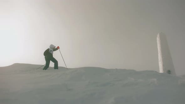 A Young Woman is Walking to the Top of a Snowcapped Mountain