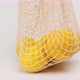 hand puts on a white surface a textile reusable string bag with ripe yellow lemon - VideoHive Item for Sale