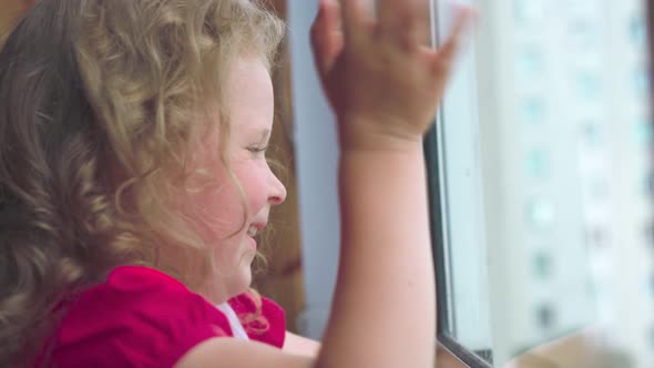 Close-up of a happy little girl seeing someone in the window.
