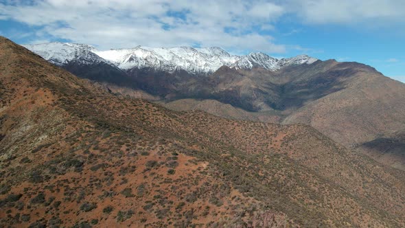 Aerial view truck right of Morro Las Papas in San Carlos de Apoquindo Park, snowcapped mountain rang