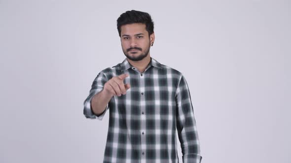 Portrait of Young Handsome Bearded Indian Man Pointing at Camera