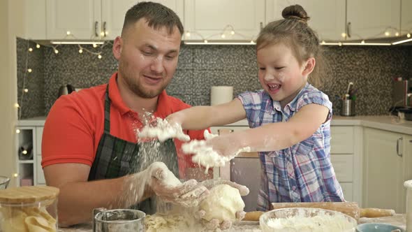 Dad and Daughter, 5-6 Years Old, Are Kneading Dough in the Kitchen. It Looks Like a Game