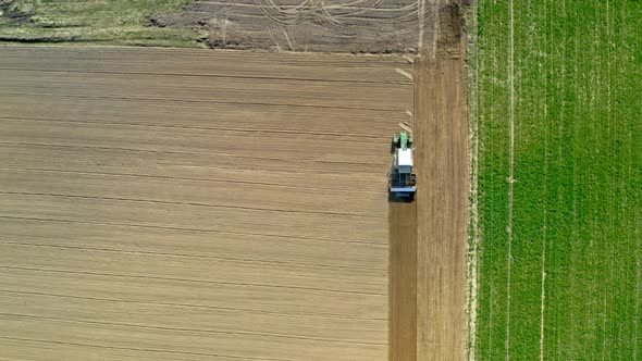 Aerial view of green tractor plowing a spring field, Poland