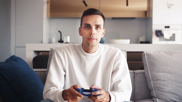 Front View of Excited Caucasian Guy Playing Video Game and Using Joystick . Handsome Young Man