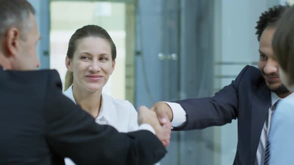 Businessmen Shaking Hands at Meeting with Female Colleagues