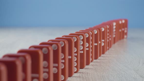 Domino Effect - a Series of Red Dominoes Falling Down the Chain on Blue Background