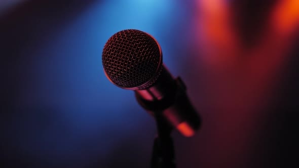 Microphone on Stage in the Dark on the Background of Multicolored Lights