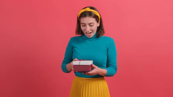 Portrait of a Happy Woman Receiving a Gift and Opening It.