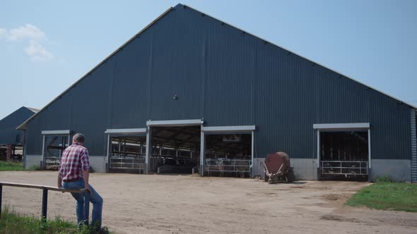 Farmer Sitting Ranch Fence Resting After Work on Modern Livestock Manufacture