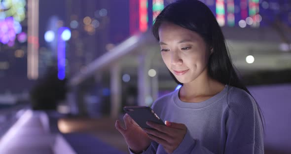 Woman look at smart phone in the city at night