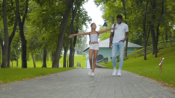 Wide Shot of Cheerful African American Girl Strolling with Brother in Sunny Park and Leaving