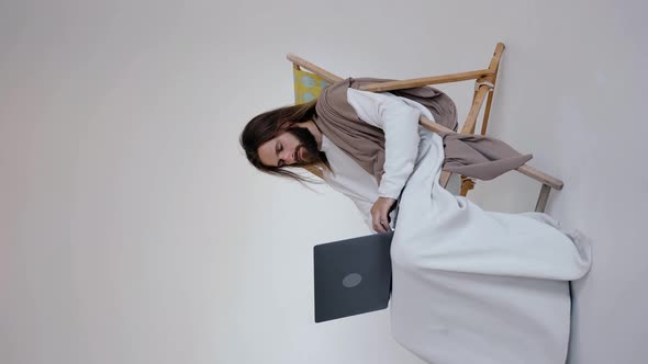 Jesus Sits in a Schizlong and Works at a Computer on a White Background