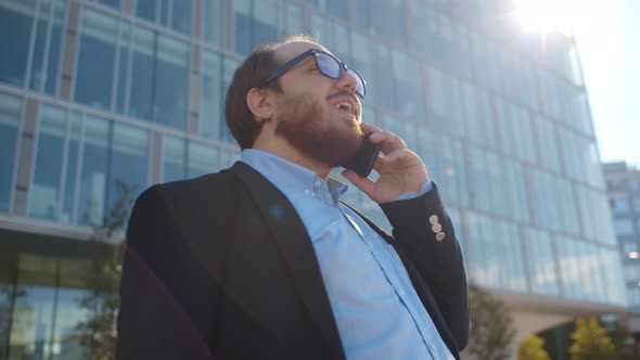 Low Angle View of Young Obese Businessman Talking on Smartphone in City Outdoors