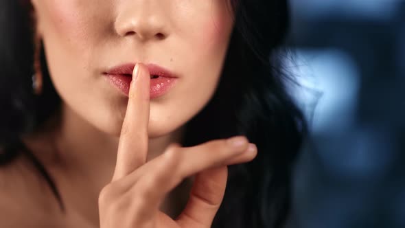 Extreme Close Up Sexy Lady Making Gesture Shh Finger Near Lips at Blue Bokeh