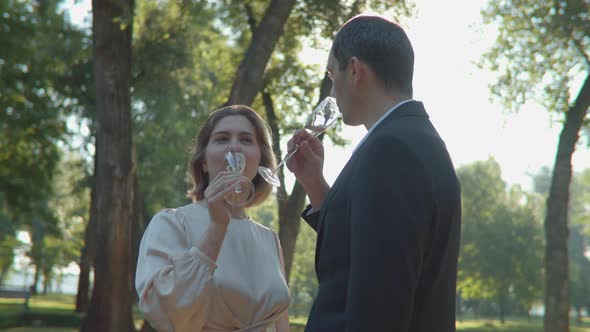 Close Up of Just Married Couple Drinking Sparkling Wine Standing in the Park