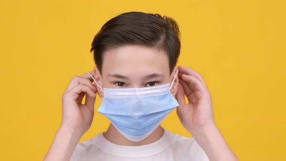 Teenager Boy Wearing Protective Face Mask Standing Over Yellow Background