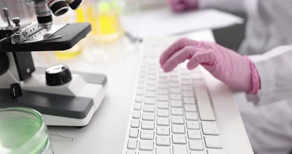 Scientist in Gloves Works on Laptop in Laboratory