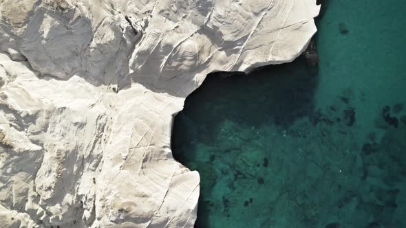 Bright white rocky cliffs cast a shadow into the crystal-clear waters of the Mediterranean Sea. Summ