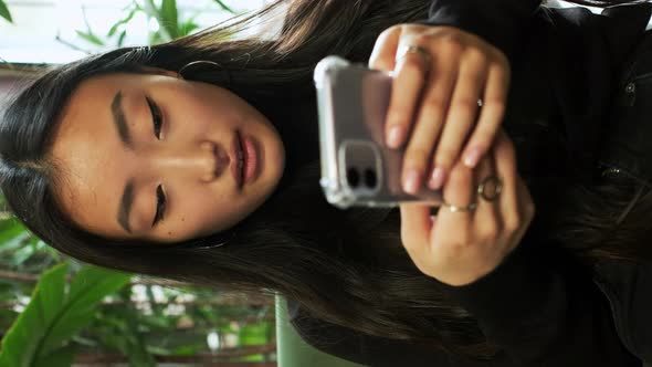 Korean Girl Sitting By The Window With Mobile Phone In Her Hands