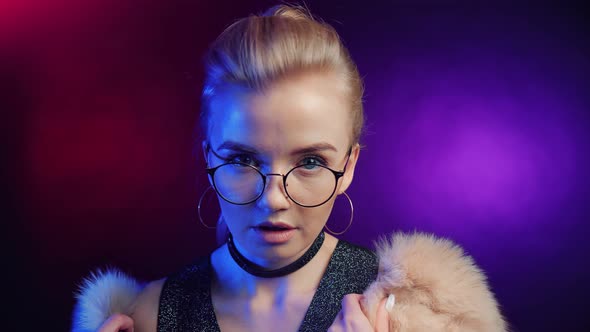 Fashionable Young Blonde Woman in Fur Coat and Glasses Dancing