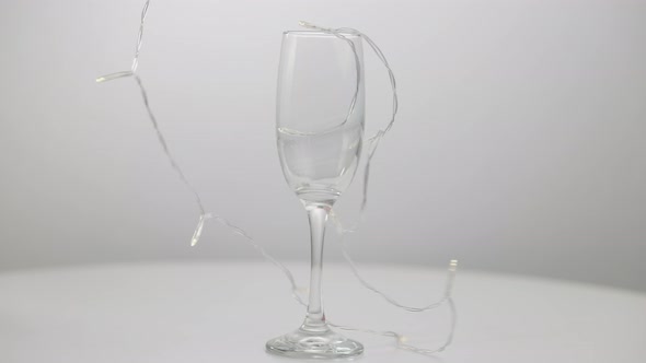 Empty Wineglass with New Year Decoration Garland Closeup