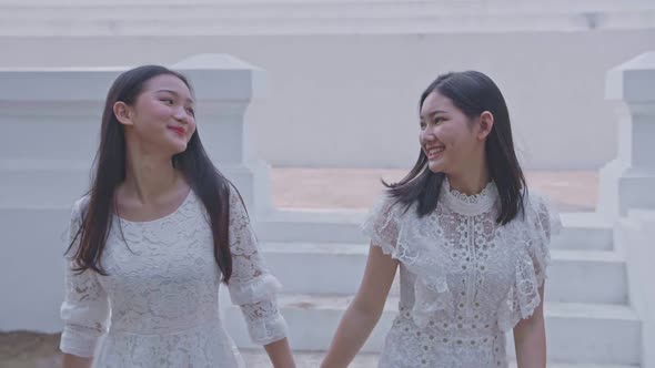 Two Asian Girls Holding Hand Walking Down Stairs On Summer Travel