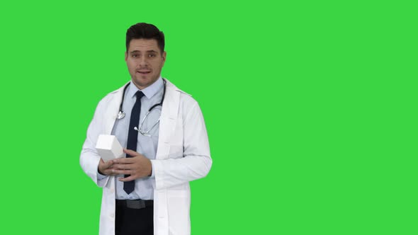 Mature Doctor in Whitecoat Describing New Pills in Box on a Green Screen, Chroma Key