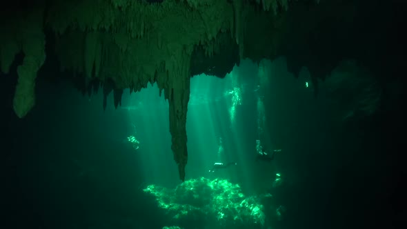 Divers in cenote sun beams