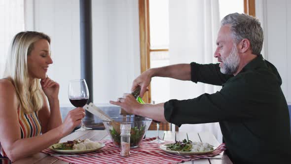 Happy caucasian mature couple smiling, talking and enjoying meal together