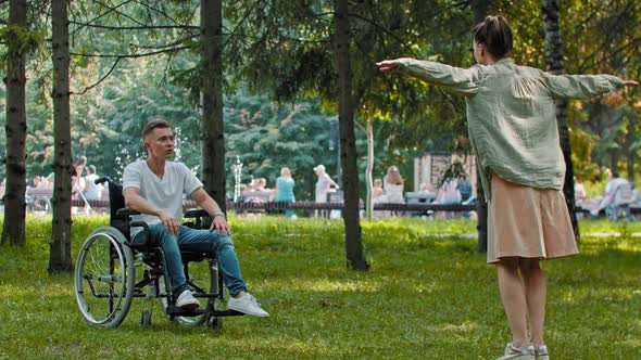 Man in a Wheelchair and His Female Friend Playing Recognizing Game in the Park