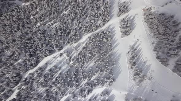 Aerial drone shot over skiers and the chair lift along the steep white snowy slopes of Verbier, Swit