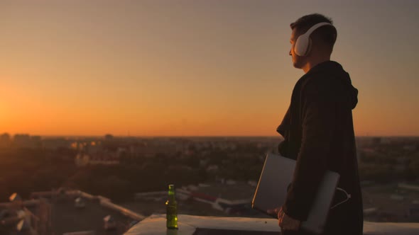 Hacker Using Laptop on Rooftop with City View and Forex Chart. Hacking and Stats Concept