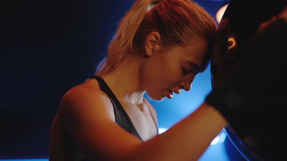 Side View of the Tired and Sweaty Woman Boxer Rested Her Head on a Punching Bag After Hard Training