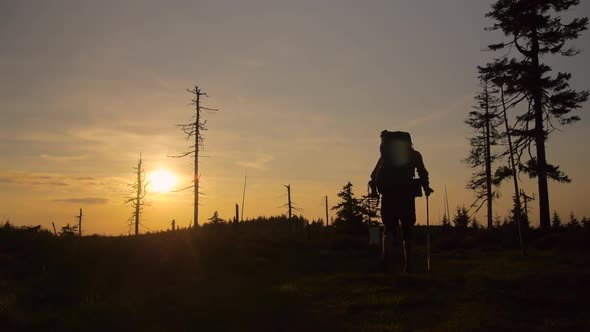 male hiker hiking with a backpack on a trail during beautiful sunset,