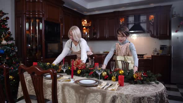 Wide Shot Portrait of Cheerful Caucasian Mother and Son Putting Christmas Decoration on Table and