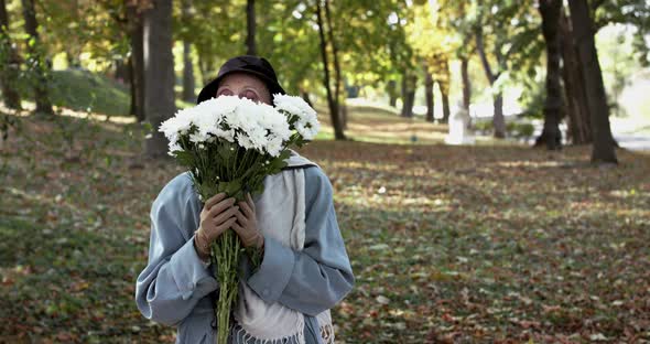 Elegant Lady in Hat Enjoying From Bouquet's Smell Looking and Smiling at Camera