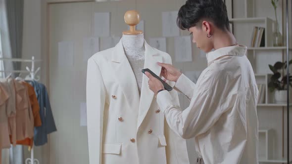 Young Asian Man Fashion Designer Looking His Phone With Clothes On Mannequin Model