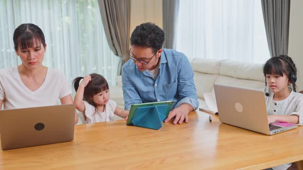 Asian busy family, young parent work from home and support daughter doing online learning.