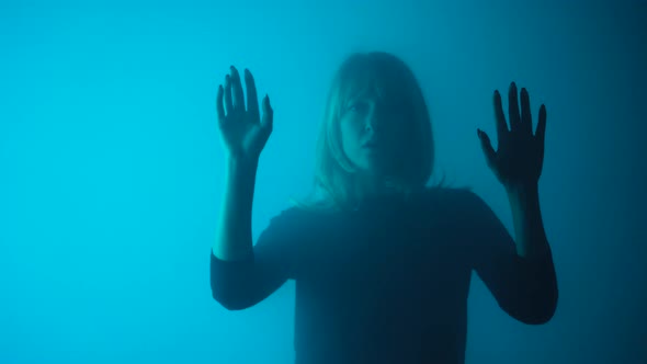 Woman Appears From Smoke Mysteriously Looks Into Camera and Touches Glass with Her Palms