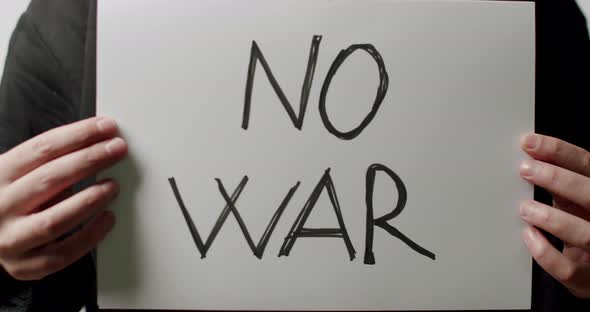 Person holding a white paper with a message No War. We Want No War Message.