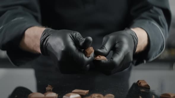 Chef Chocolatier Breaks Chocolate Bar To the Small Pieces for Melting and Making Sweets, Raw