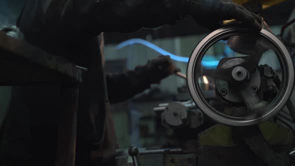 White Man Rotates the Wheel of a Takor Machine in the Carpentry Workshop of a Large Factory