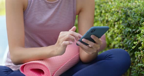 Sport woman use of mobile phone with her yoga mat