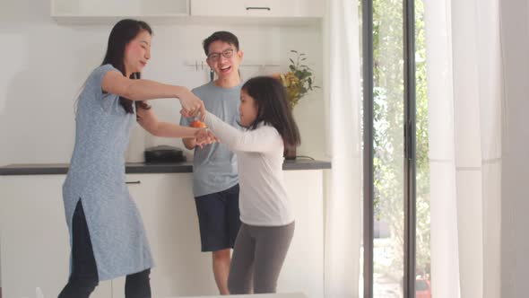 Happy young Asian family listen to music and dancing after breakfast at home.
