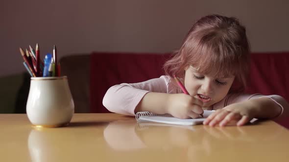 Cute Child Girl Artist Studying Drawing Picture with Pen and Pencils at Home