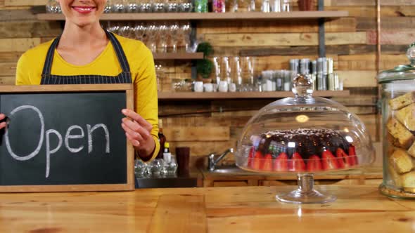Smiling waitress showing slate with open sign
